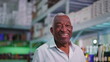 © Marco - Portrait of a joyful Black Senior Brazilian man smiling at camera standing inside supermarket laughing