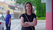 Portrait Of A Serious Caucasian Woman With Arms Crossed Standing In Sidewalk Looking At Camera In Urban Setting. Judgemental Female In 40s Person
