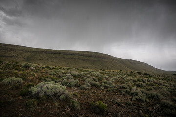 Sage brush desert below rolling mesas in desert terrain near Twin Falls Idaho with stormy skies