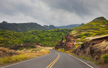 Winding Road With Traffic Sign And Cloudy Sky Through The Green Hills Along A Scenic Drive In West Maui; Maui, Hawaii, United States Of America