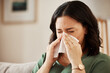 © Malik/peopleimages.com - Tissue, blowing nose and woman in a living room with flu, cold and hay fever, crisis or viral infection in her home. Sneezing, allergies and person with health risk in a lounge or coughing illness