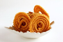 Indian Traditional Homemade Tea Time Snack Chakli Or Chakri A Spiral Ring Shaped Crispy Deep Fried Snack Also  Known In India As Chakali, Murukku, Muruku, Murkoo In Bowl On White Background