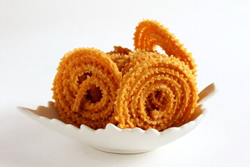 Indian Traditional homemade Tea Time Snack Chakli or chakri a spiral ring shaped crispy deep fried snack also  known in india as Chakali, Murukku, Muruku, Murkoo in bowl on white background