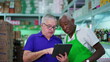 © Marco - Senior Manager Presenting Tablet Screen to Senior African American Grocery Store Employee
