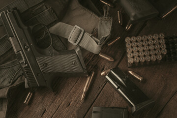 A man is disassembling a gun above the wood table. Black gun, male hands and wooden table underneath.