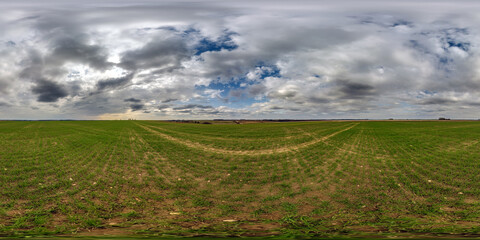 Wall Mural - spherical 360 hdri panorama among green grass farming field with clouds on overcast sky in equirecta