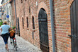 zdjęcie rowerzysty przy średniowiecznym  ceglanym murze przy kamiennej ulicy