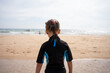 Little girl surfer in wetsuit standing ocean beach
