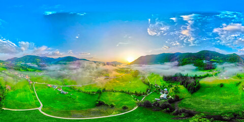 Wall Mural - Aerial drone panorama of small beautiful landscape in Slovenia at foggy dawn. Beautiful summer morning landscape.