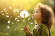 Cute little girl blowing dandelions in a sunny flower meadow