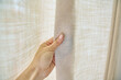 © Valerii Honcharuk - Light beige sand linen natural curtains on window, close-up of hand touching curtains