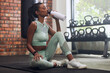 Woman, tired and drinking water on floor at gym in workout, training or exercise for fitness, health or wellness. Young indian girl, bottle and hydration for body development, commitment or hard work