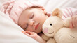 © Justlight - A sleeping baby peacefully nestled ast soft cream blankets snuggling a pink plush toy