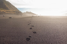 black sand beach with footprints concept follow the path