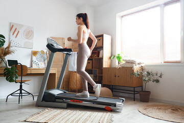 Canvas Print - Sporty young woman training on treadmill at home