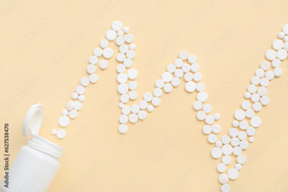 Bottle with cardiogram made of white pills on yellow background