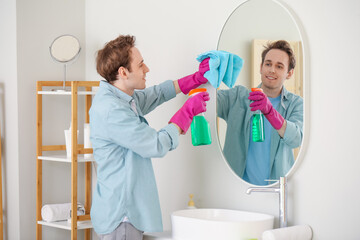 Canvas Print - Young man cleaning mirror in  bathroom