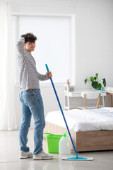 Wall Mural - Young man mopping floor in bedroom