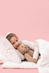 Wall Mural - Little girl with toy and soft blanket lying on pink background