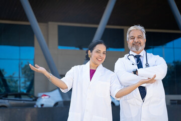 Poster - Indian senior doctor standing with female doctor and giving happy expression