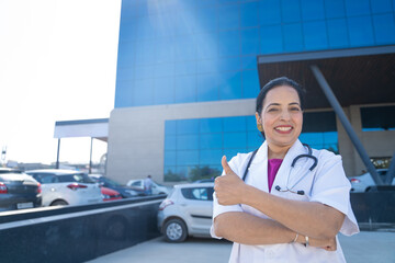 Wall Mural - Indian female doctor standing out of hospital and showing thumps up.