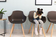 Sad african american girl patient sitting in waiting room at hospital, copy space