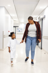 Wall Mural - African american girl patient and her mother walking in corridor at hospital