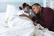© WavebreakMediaMicro - African american girl patient lying on bed with oxygen mask, with her mother at hospital