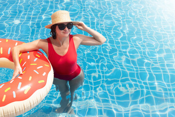 Wall Mural - Beautiful woman with inflatable donut in pool