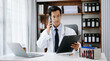 © Nuttapong punna - Man doctor phone call, healthcare talking and medical service writing sick note, surgery planning and prescription.and clinical report test results in office