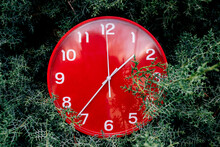 Red Clock Placed On Green Meadow During Daytime