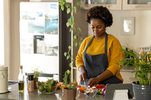 Plus Size African American Woman In Apron Chopping Vegetables In Kitchen
