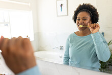 Happy Plus Size African American Woman Brushing Teeth In Bathroom