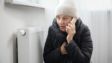 Portrait Of Stressed Brunette Woman In Winter Coat And Woolen Hat Calling Service To Repair Broken Heater Radiator