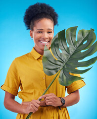Wall Mural - Fashion, portrait and black woman with plant on blue background for eco friendly, organic and natural clothes. Nature, happy and female person with monstera leaf for sustainable clothing in studio
