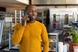 © Wavebreak Media - Happy african american male bakery worker wearing yellow sweatshirt and talking on smartphone