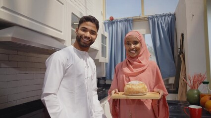 Wall Mural - Happy couple wearing traditional outfits from the emirates spending  time in the kitchen of their beautiful modern apartment in Dubai