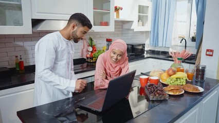 Wall Mural - Happy couple wearing traditional outfits from the emirates spending  time in the kitchen of their beautiful modern apartment in Dubai