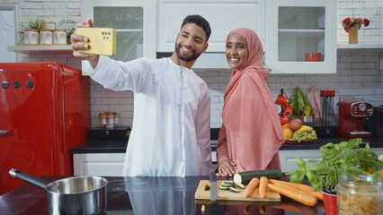 Wall Mural - Happy couple wearing traditional outfits from the emirates spending  time in the kitchen of their beautiful modern apartment in Dubai