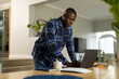 © Wavebreak Media - African american man standing at table using laptop at home