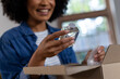 © Wavebreak Media - Happy biracial woman unpacking parcel at home