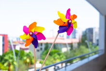 Colorful Windmills On Balcony In Selective Focus. Windmills With Wings Of Different Colors. Clean Energy, LGBTQ Colors Concept.