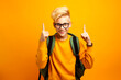 schoolboy in glasses with backpack ready go to school for education, pointing up with index finger