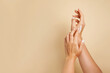 © Nastya - Beautiful young woman hands with cosmetic cream. Woman applies cream on her hands on beige background, copy space