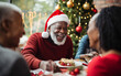 © Malchevska Studio - Smiling senior black african american dark-skinned man celebrating christmas with his family at the holiday table