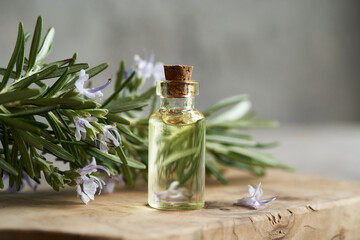 Wall Mural - A bottle of aromatherapy essential oil with fresh rosemary leaves and flowers