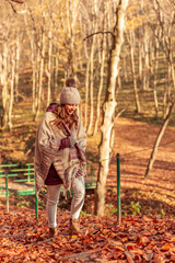 Woman walking through the forest on an autumn sunny day