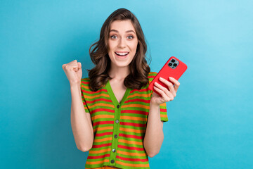 Poster - Photo of young woman brown curls raised fist up reading optimistic news online smartphone social medias isolated on blue color background