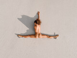 Aerial view of naked woman sunbathing on beach near the ocean. Woman with good stretch.