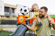 © Petro - Father with son holding football ball and having fun at the playground